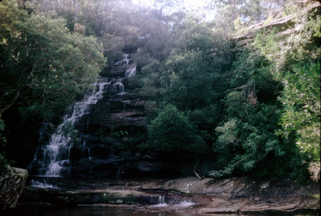 Cascading middle to left waterfall, with bushes up the sides of the hill