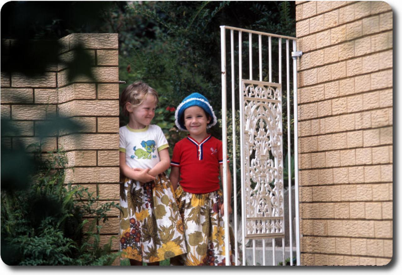 Little boy and girl at gate - in identical dresses