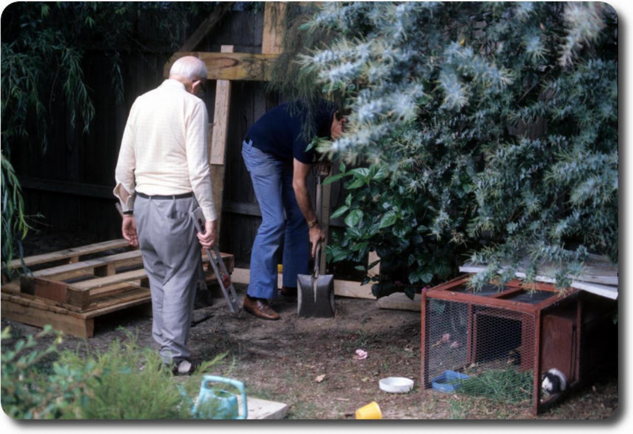 Two men preparing ground for wooden frame assembly