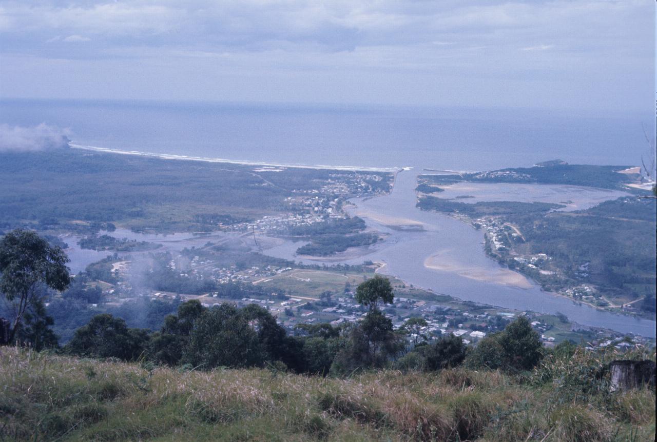 Looking down from mountain to small town at river mouth, with ocean beaches and breaking surf