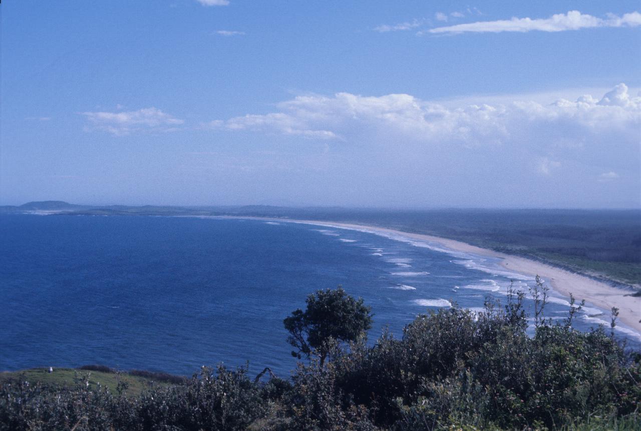 View from headland, south, with sandy beach, breaking waves and distant headland