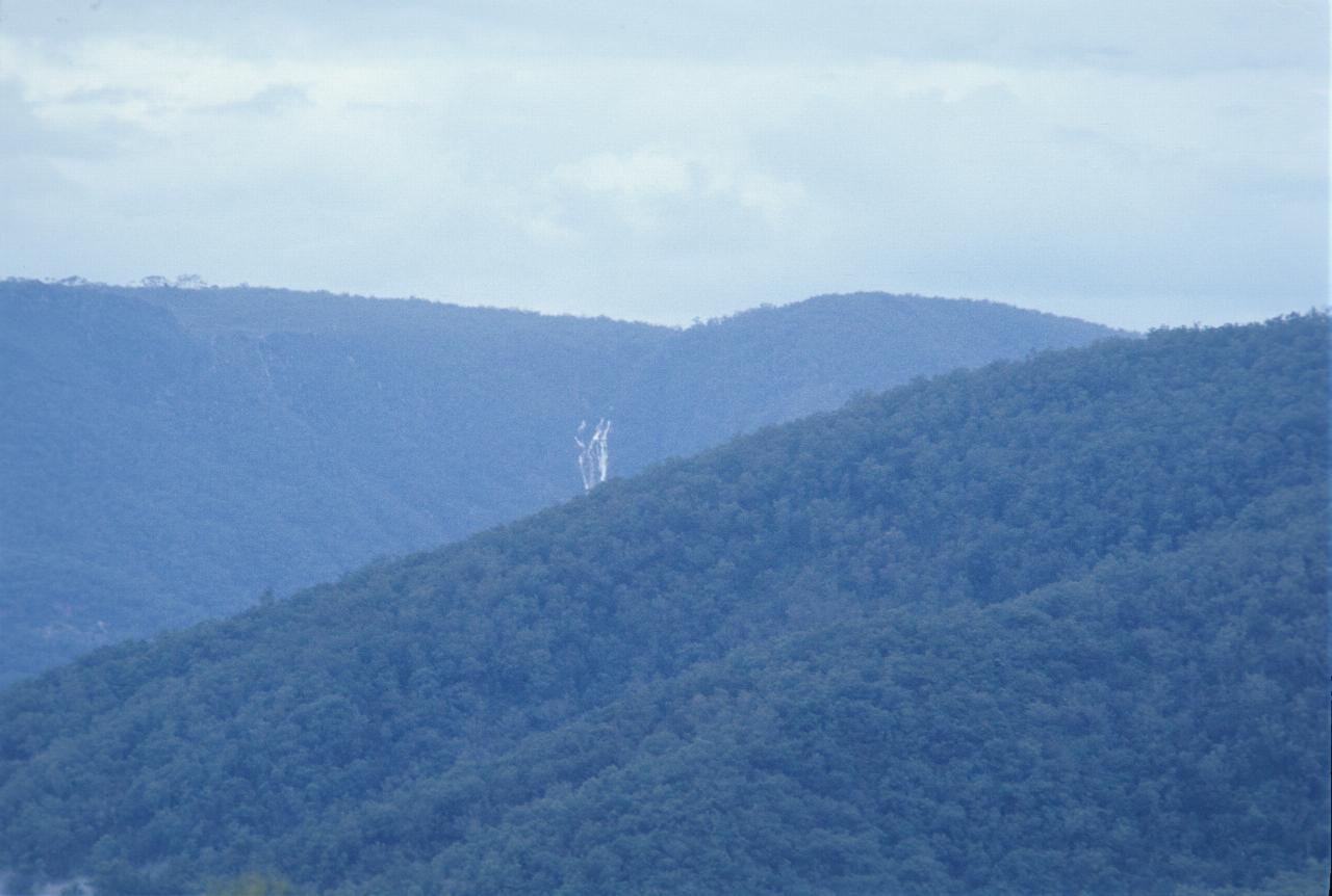 Waterfall on distant hill, somewhat obscured by nearby hill