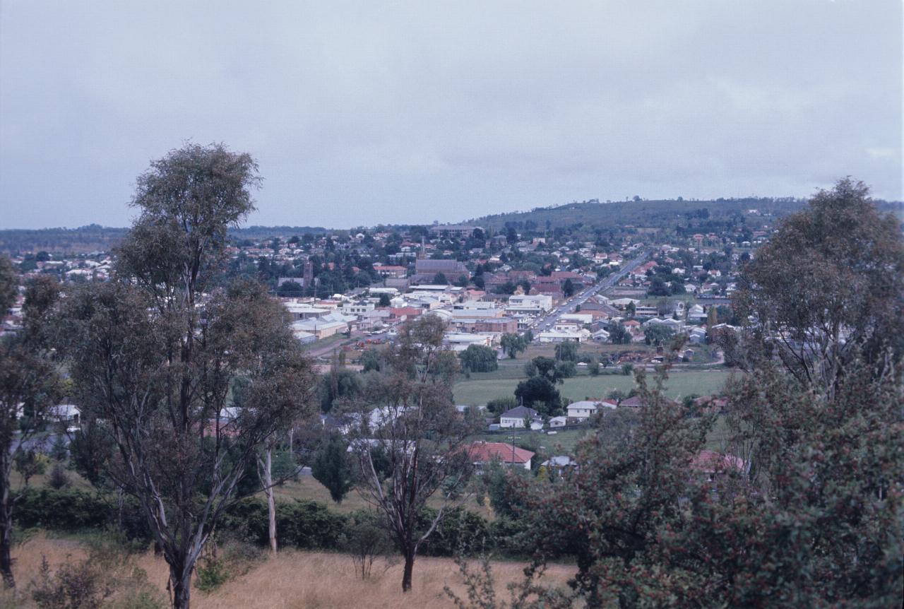 View from hill over central core of commercial buildings surrounded by homes and trees