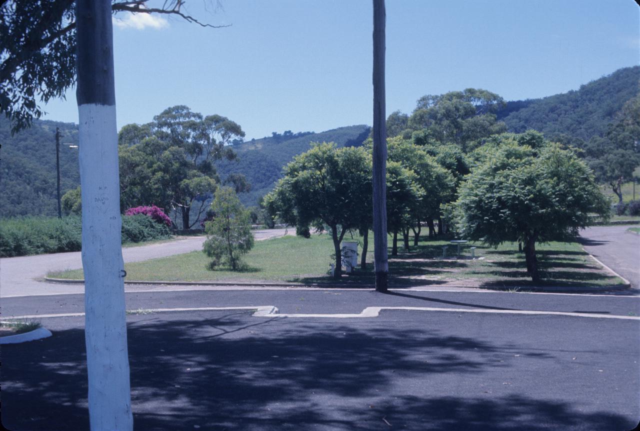 Parking area with small trees, hills behind