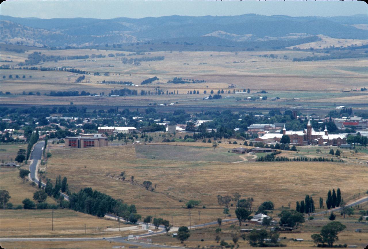 Hilltop view over part of town and fields to distant hills