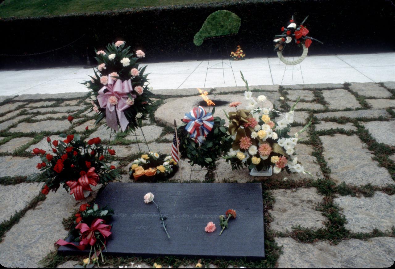 Dark marble grave stone with flower arrangements