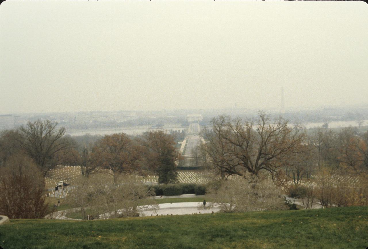 Trees loosing leaves, looking towards barely visible white marble building across a river