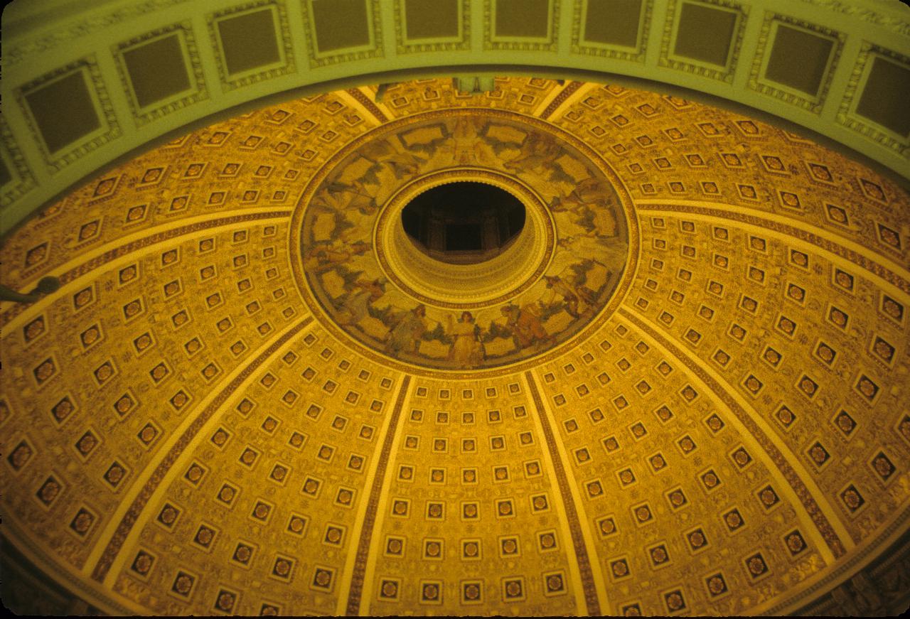 Looking up into the inside of a dome, with gold paint and other decorations