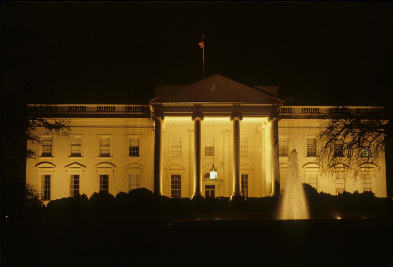 White, two storey building with portico and large pillars, and fountain out the front.