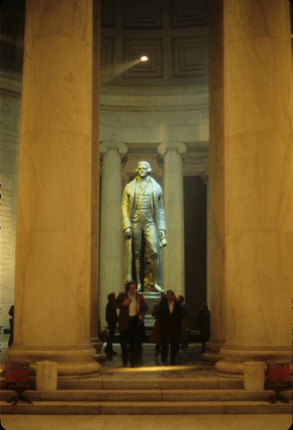 Statue of man, on pedestal, in building with large pillars at the front