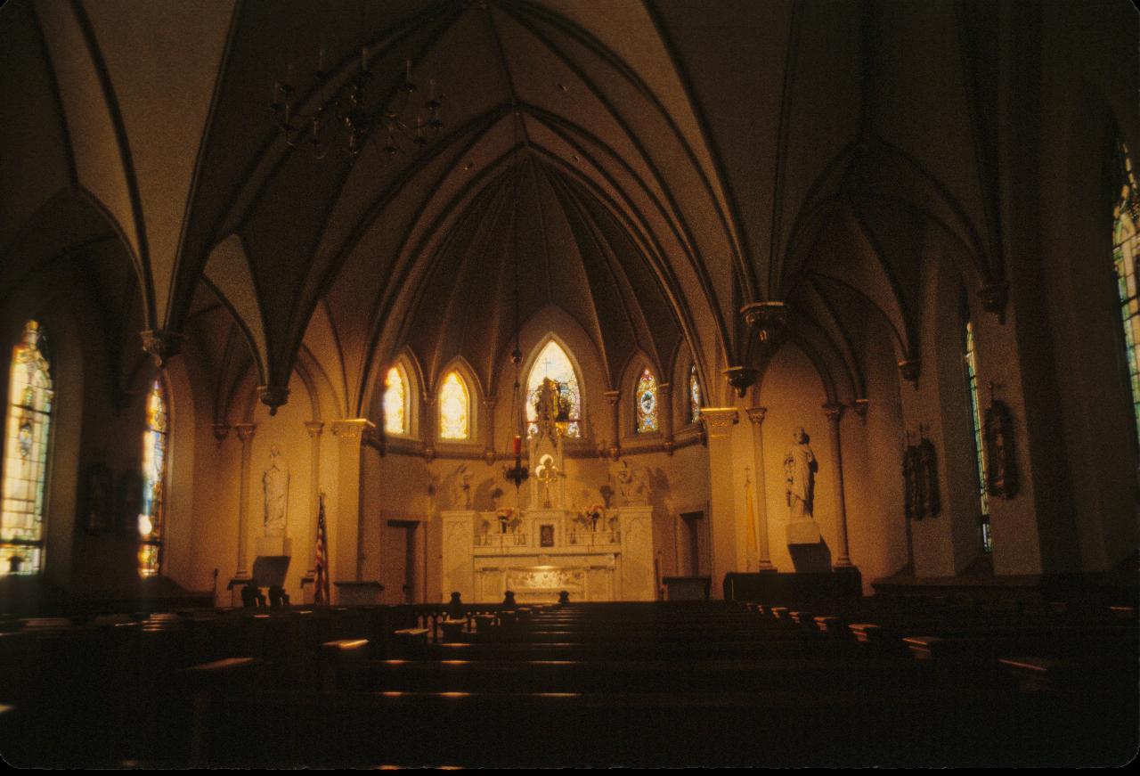 Inside church, with vaulted ceiling, pews and altar at far end