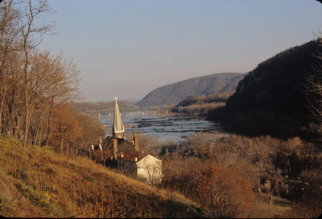 From side of hill, with church steeple and view of river and distant bridge