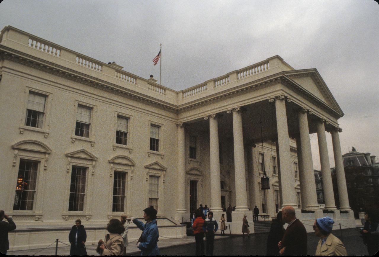 Two storey white building, with large portico supported by large columns