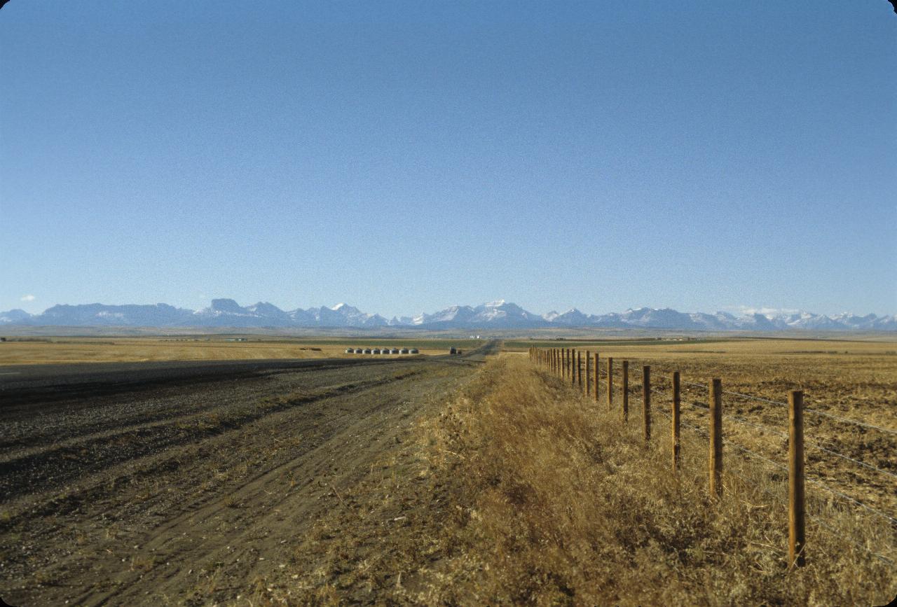 Flat plains, brown grass and distant mountains, snow on peaks