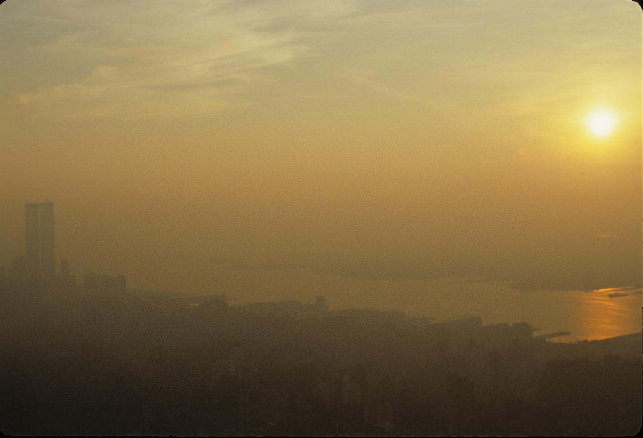 Sun sinking over hazy River and city below