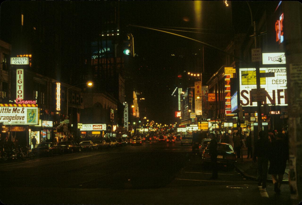 Night street scene with people, cars and theatre marquees