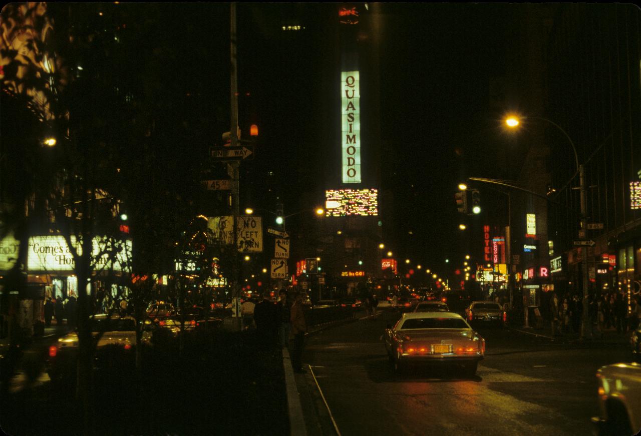 Night street scene with people, cars and theatre marquees