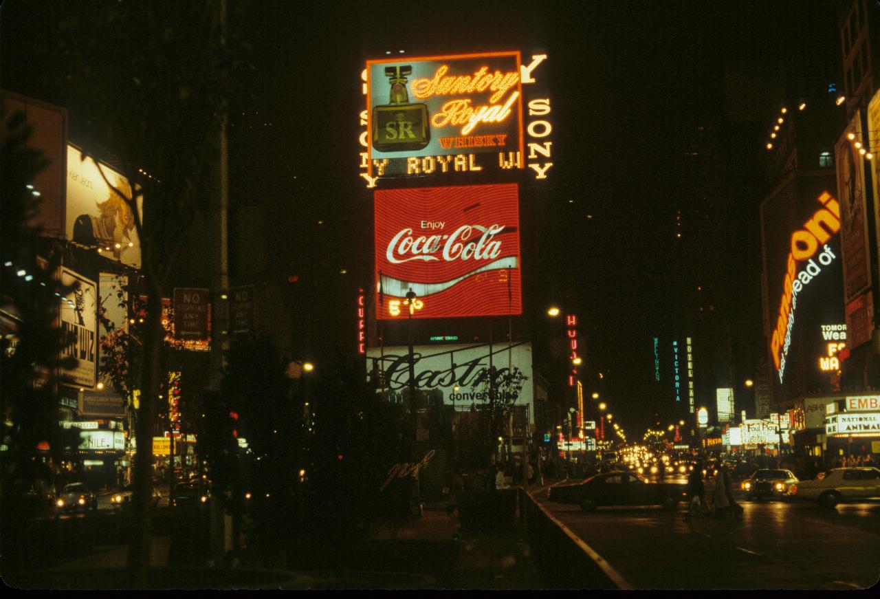 Night street scene with people, cars and theatre marquees