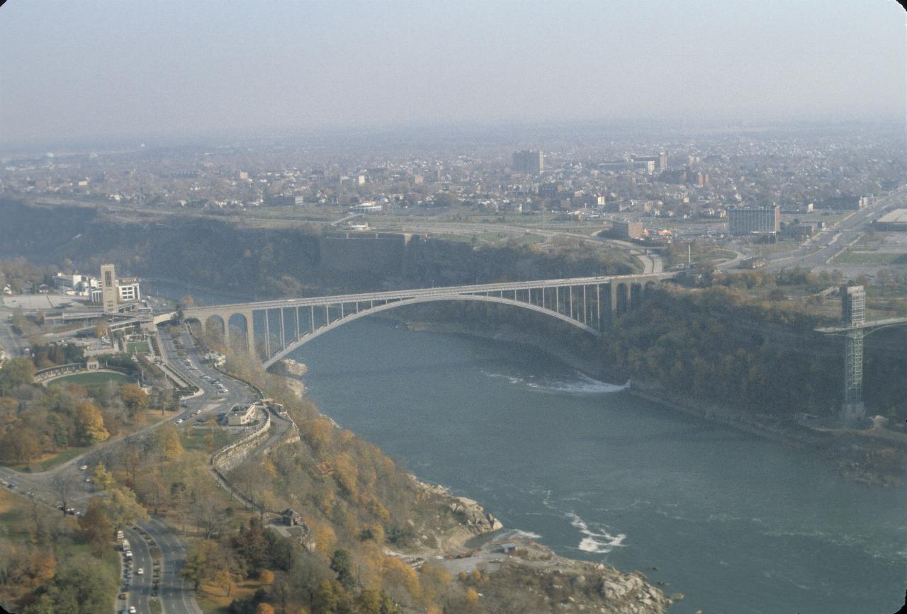 Arch bridge across canyon carrying river away from camera