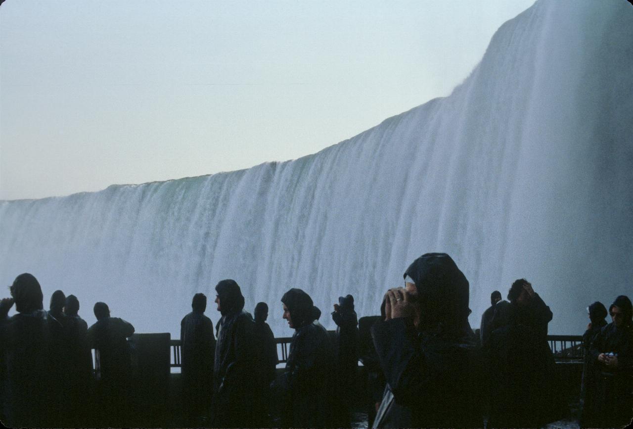 People in rain gear in front of rushing water of the falls