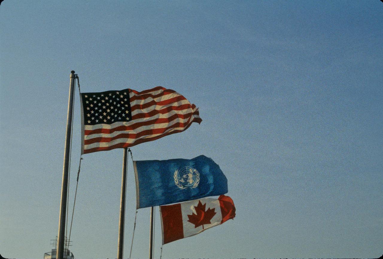 Three flags on poles: US, UN and Canada