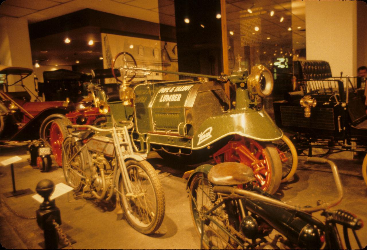 Several early petrol driven vehicles, including a couple of cars and several motorcycles