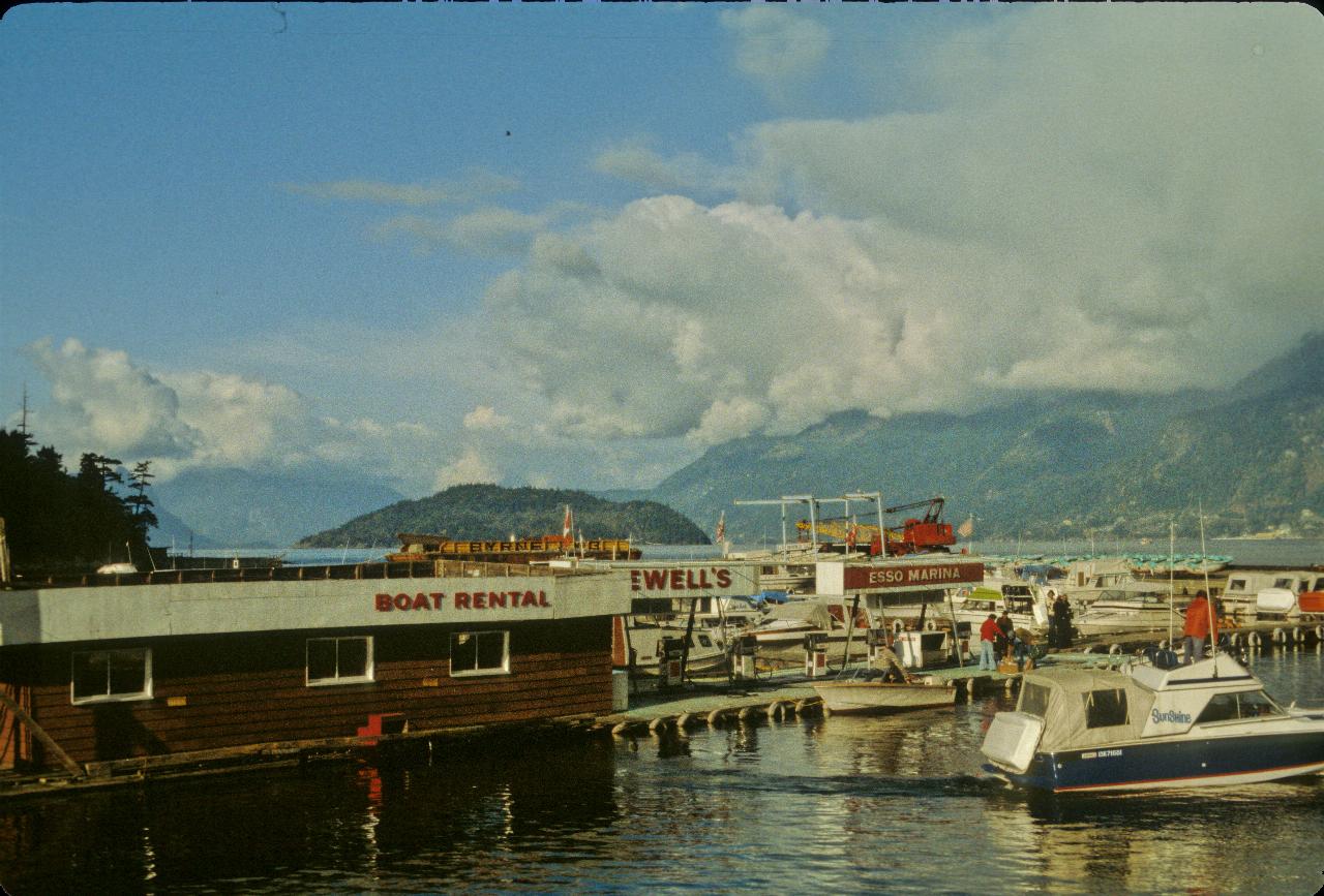 A few pleasure boats and fueling dock, with hills and an island in the background