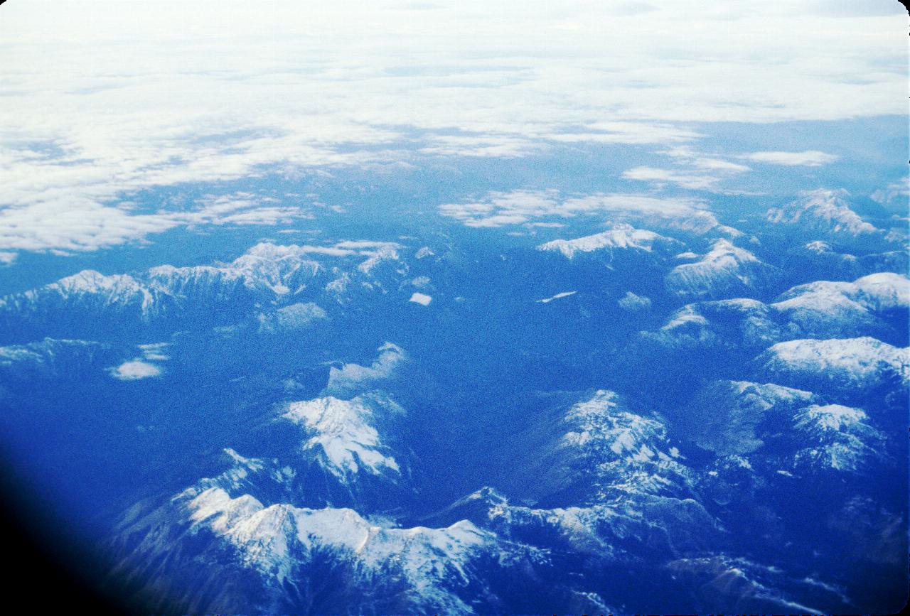 View from the plane of snow capped mountains and some clouds