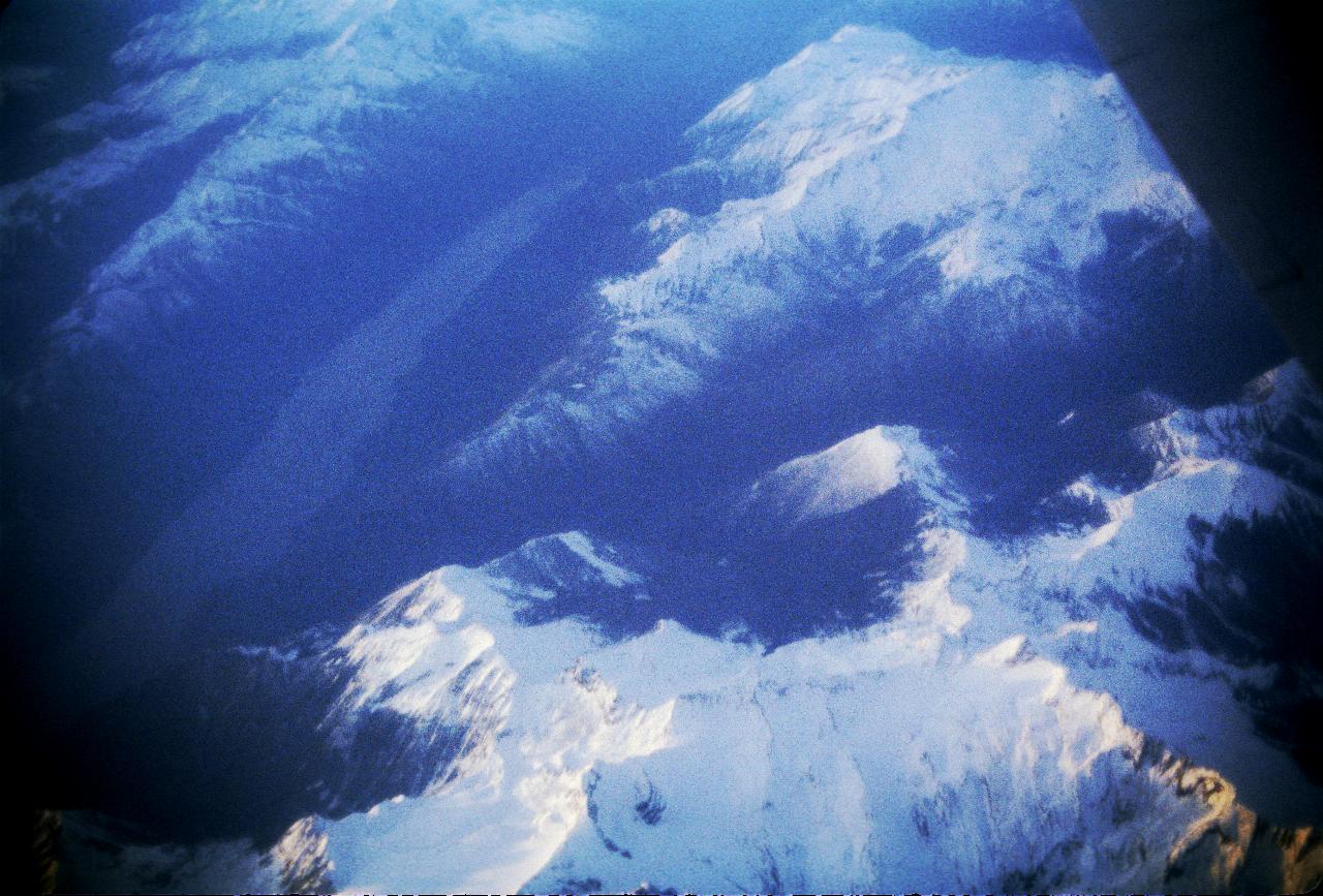 Closer view of snow capped mountains, and a lake or dam below them