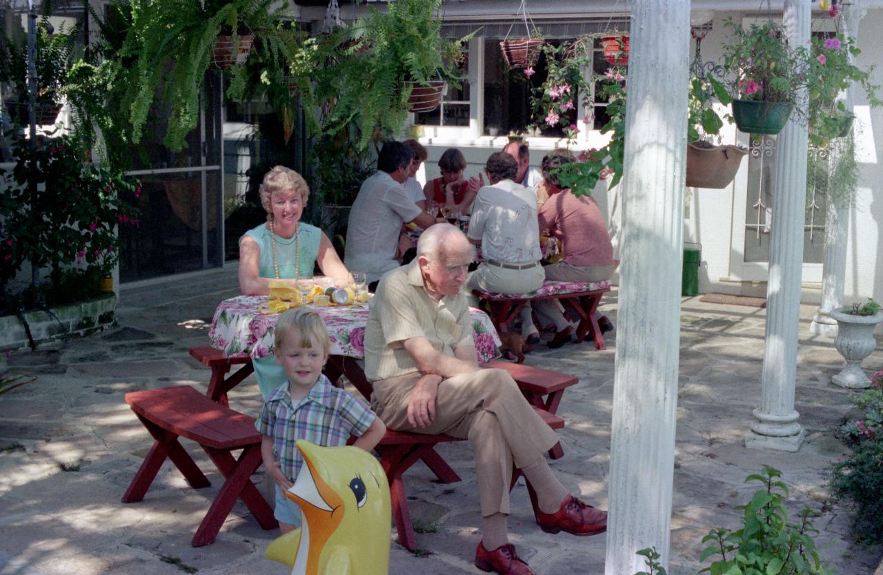 Two round tables, people seated and talking, under pergola