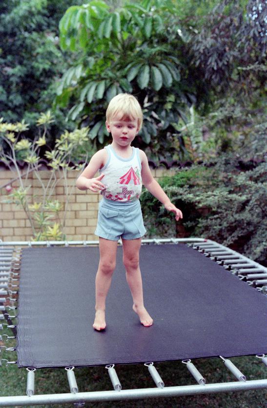 Young boy standing on trampoline in garden