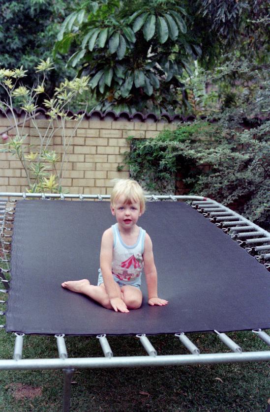 Young boy sitting on trampoline in garden