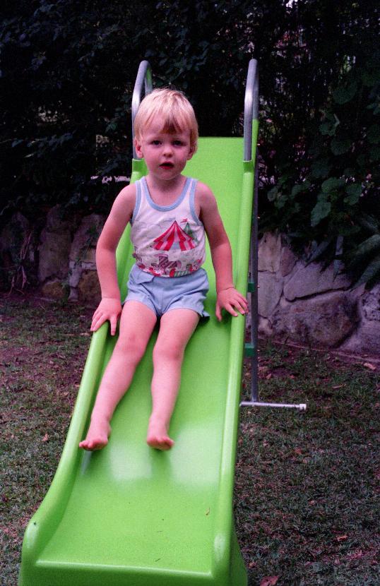 Young boy sliding down a bright green slippery dip