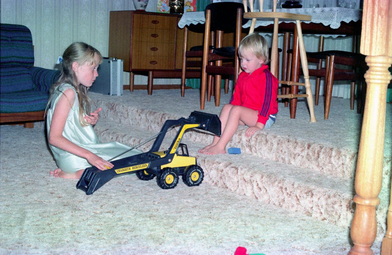 Little girl playing with Tonka front loader and little boy watching