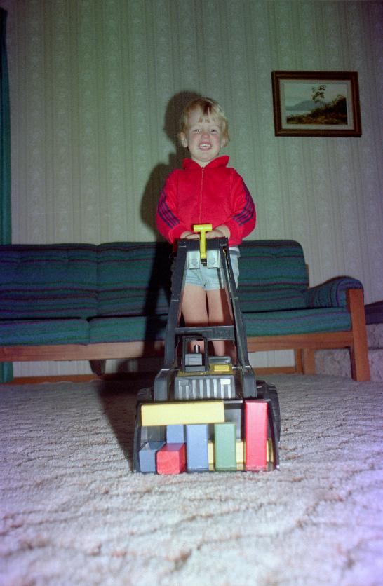 Happy little boy pushing front end loader with toy blocks in it