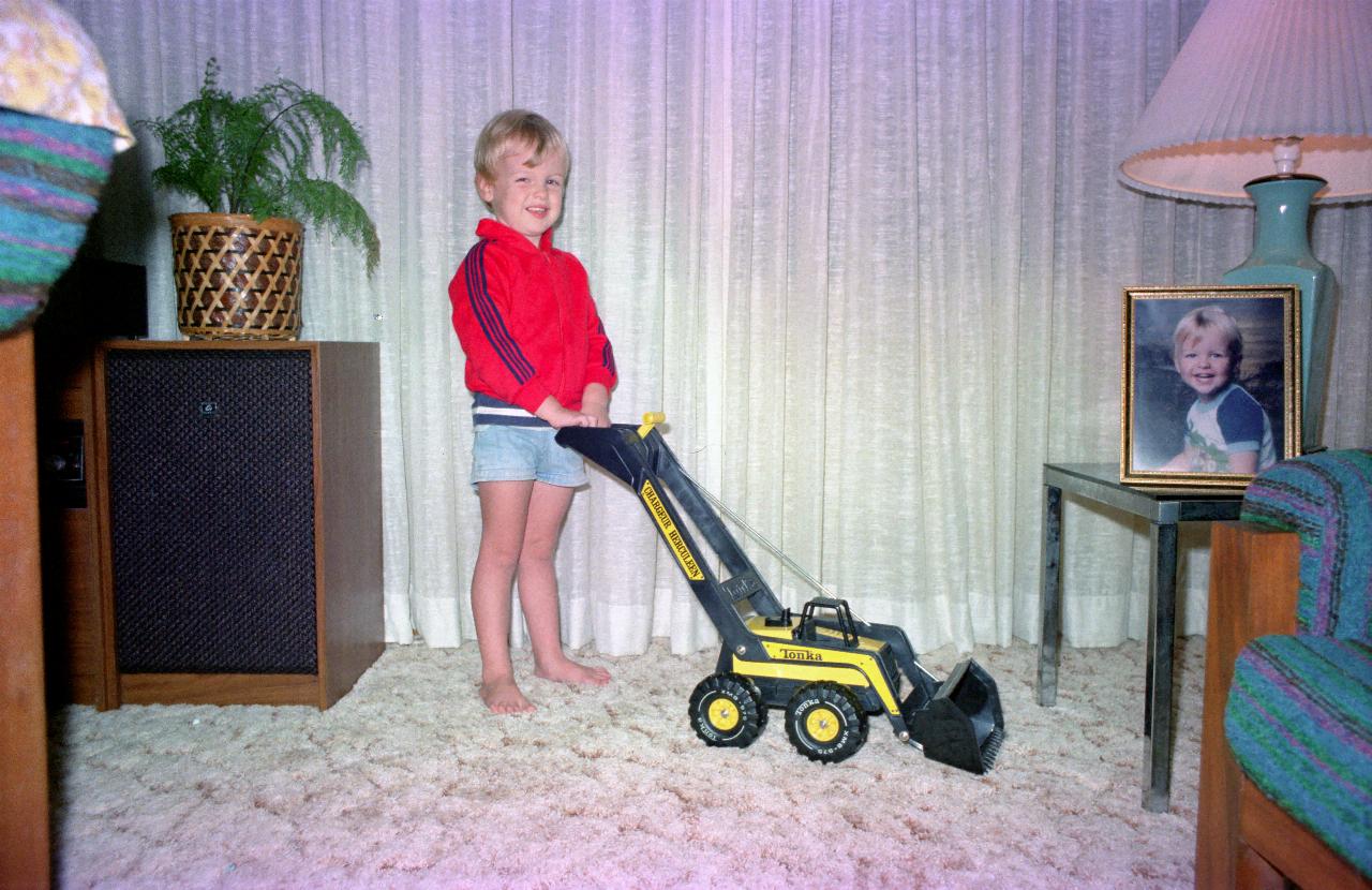 Happy little boy pushing Tonka front end loader in lounge room