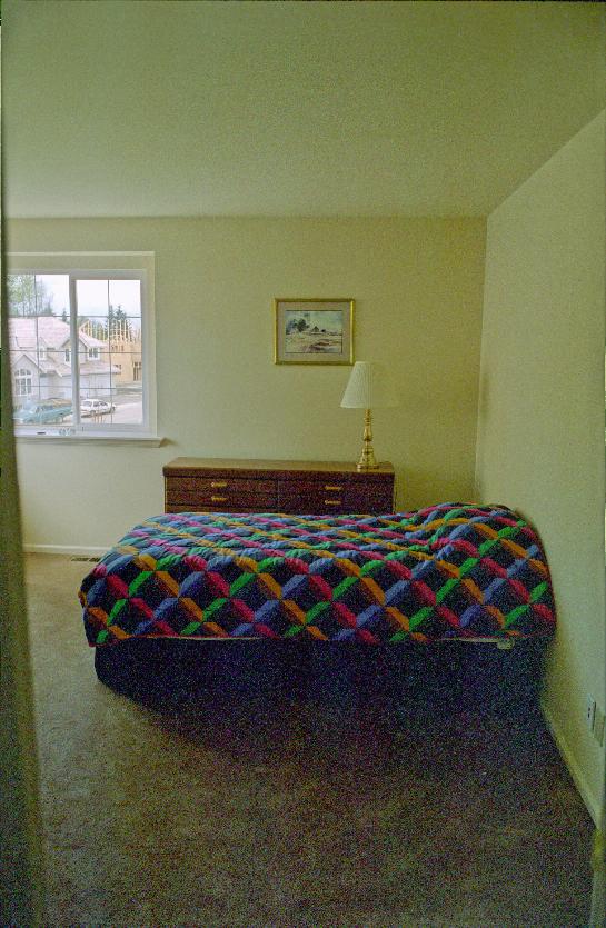 Bedroom with bed, dresser, lamp and print on wall