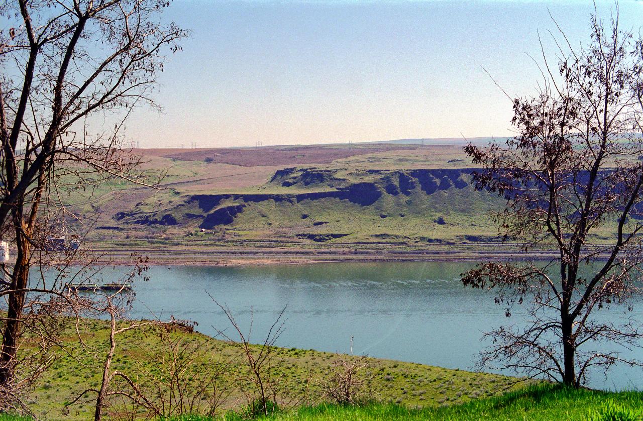 View directly across broad river to wheat fields on low cliffs