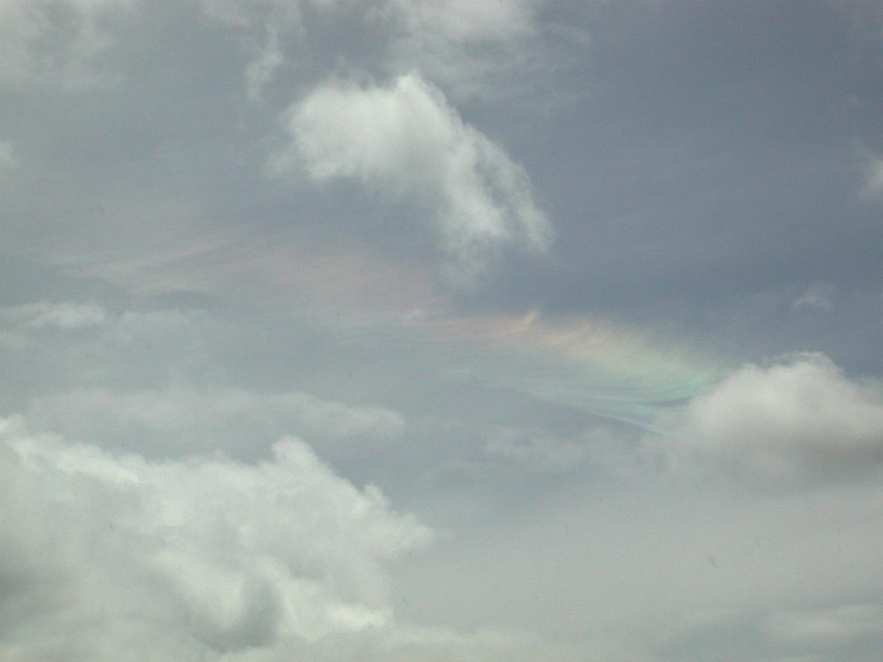 Cloud on sky with rainbow around one of the clouds