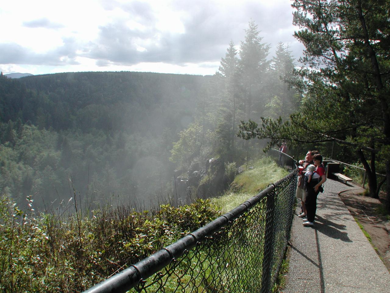 Mist rising up the valley wall from bottom of waterfall and covering tourists