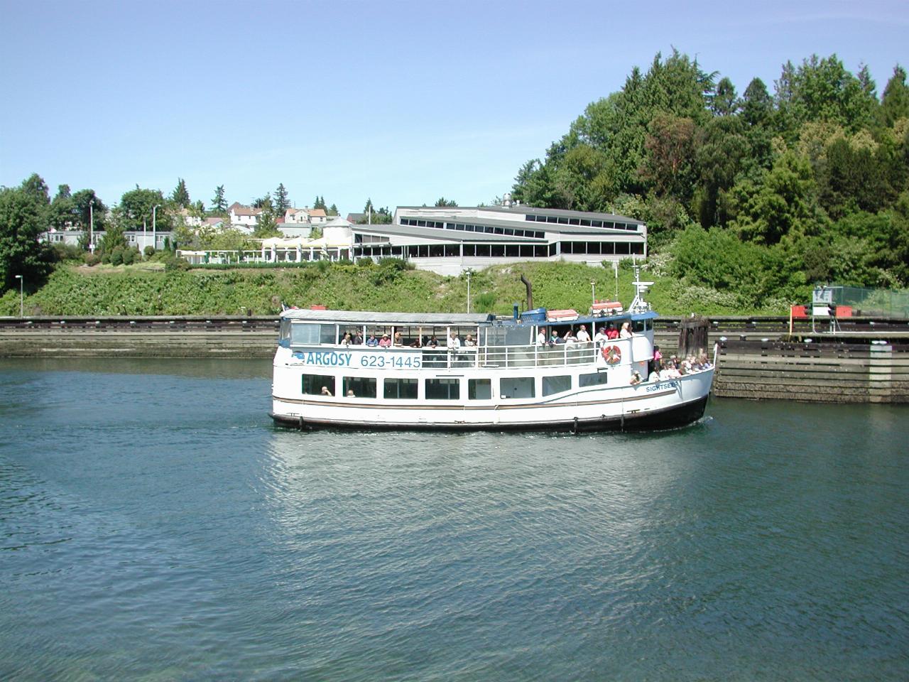 A smallish tour boat powering towards the lock entrance from downstream