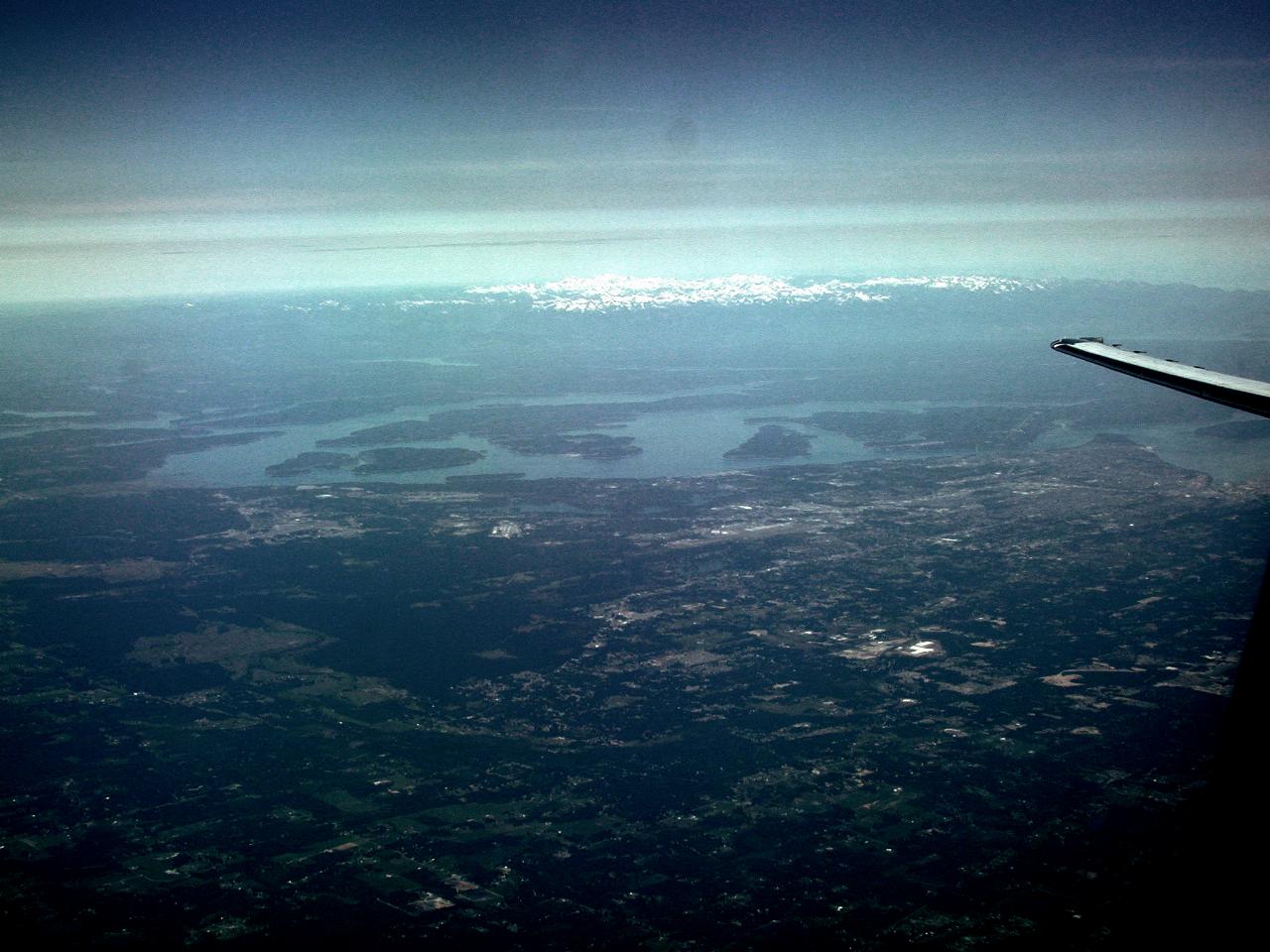 Mostly rural area with water passages and distnaant snow covered peaks