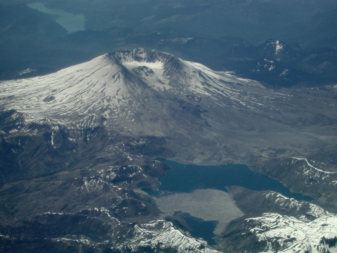 Damaged volcanic peak and lake with logs on surface