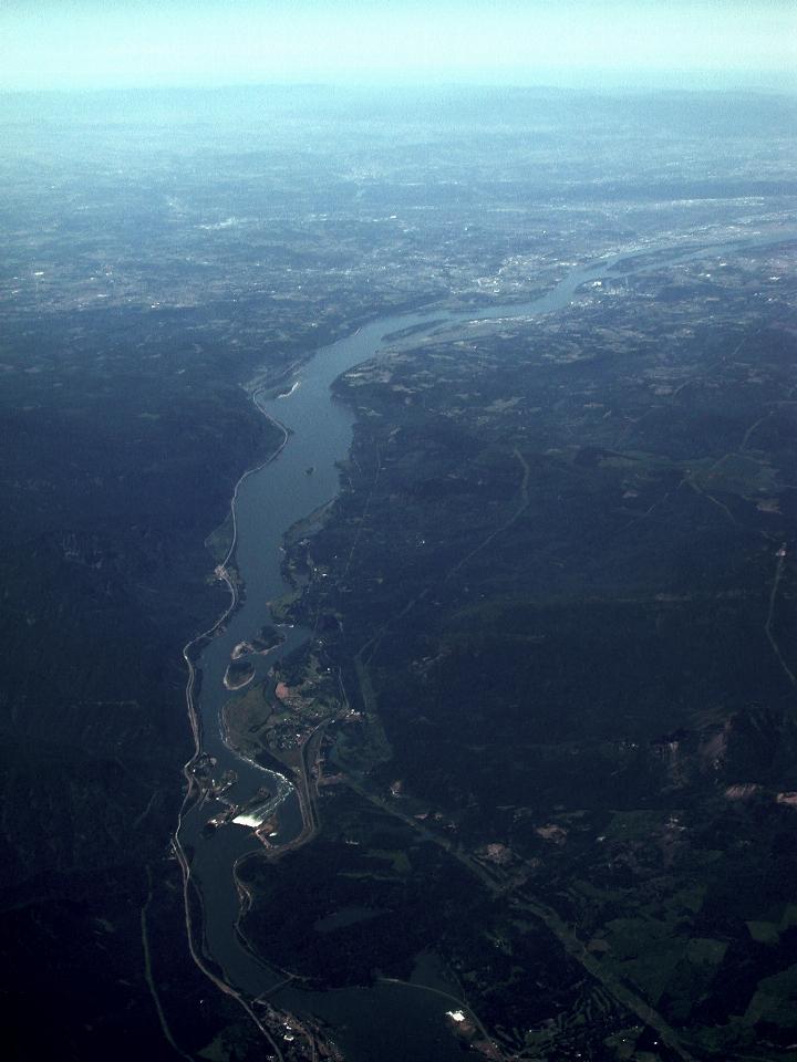 Long view looking down wide river over dam with spillway