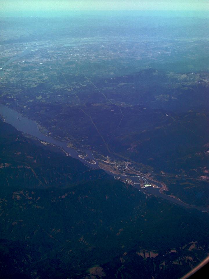 Long view looking down wide river over dam with spillway