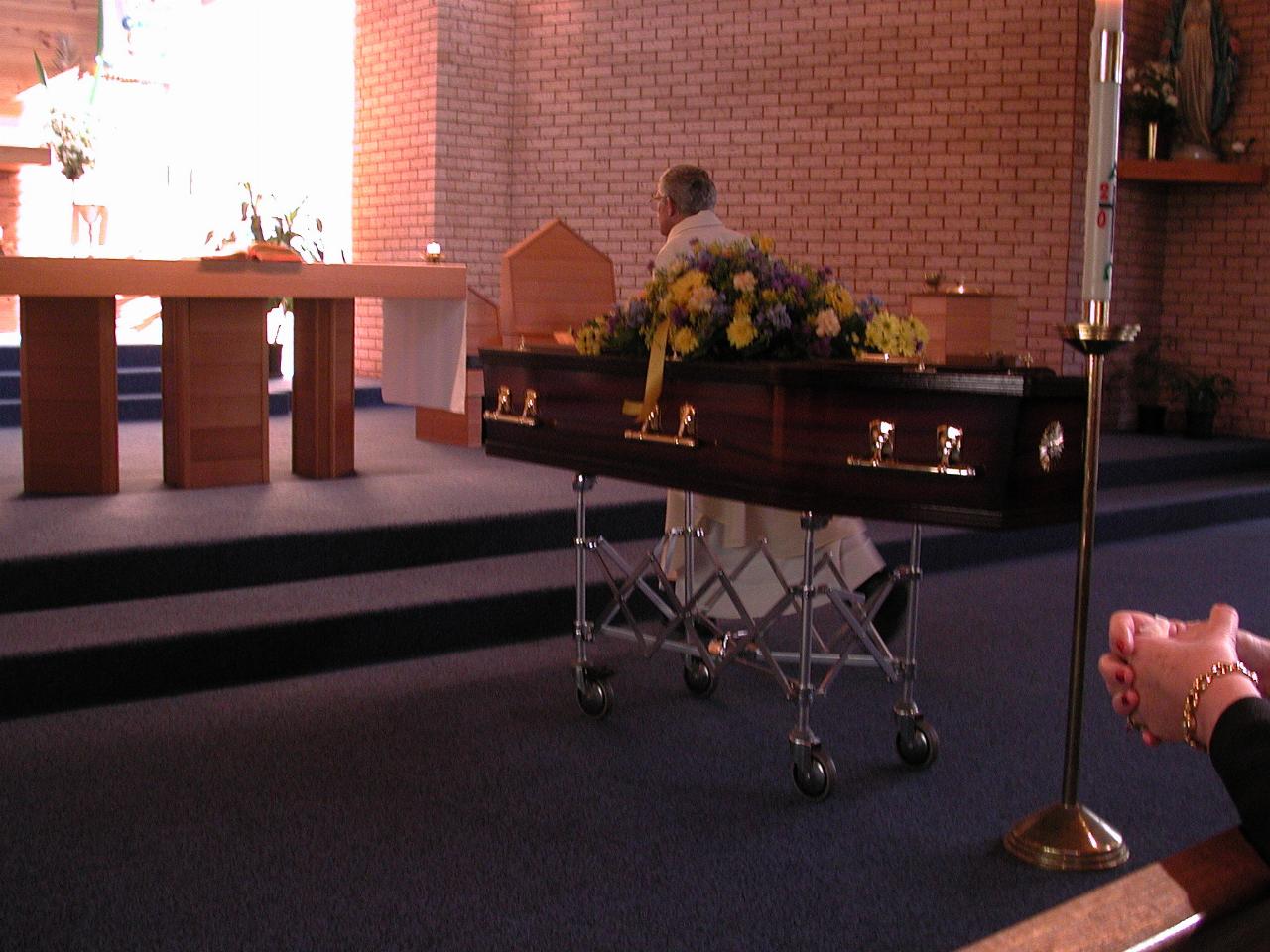 Priest passing coffin at front of the church