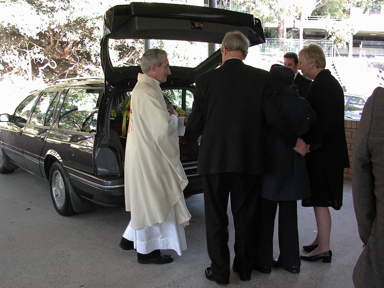 Priest with family at back of hearse