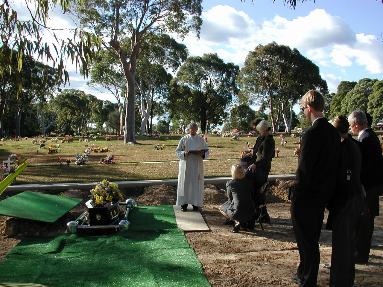 Priest and family around the grave