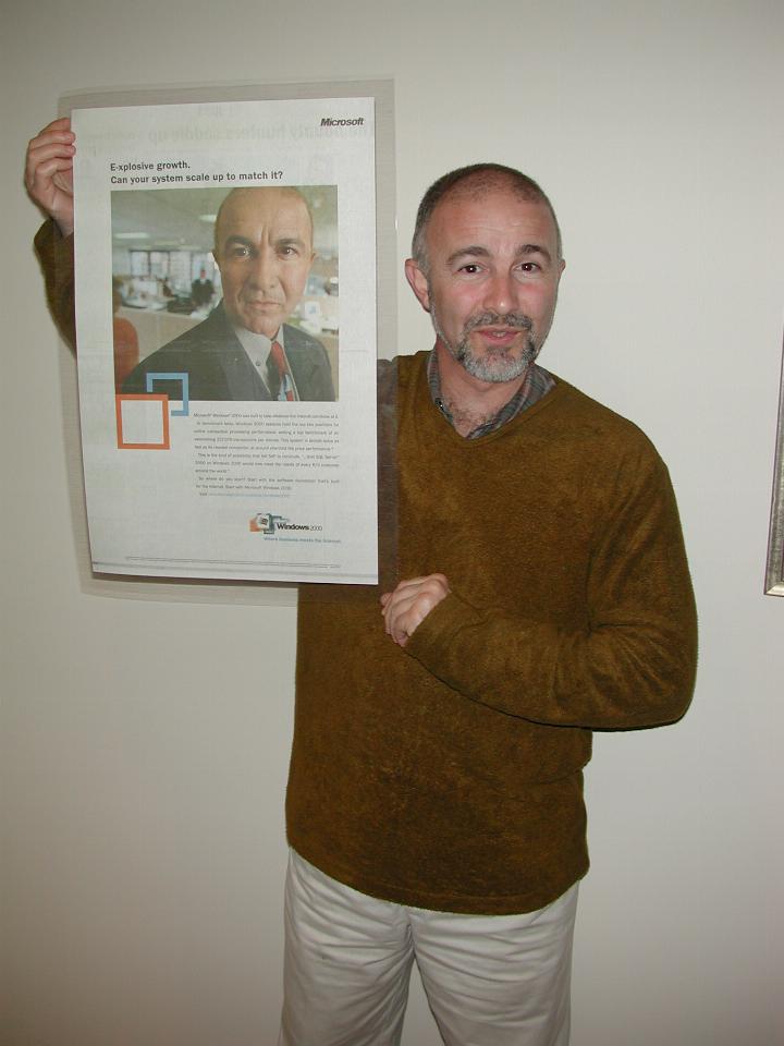 Man holding broadsheet newspaper page with his face in an advertisement