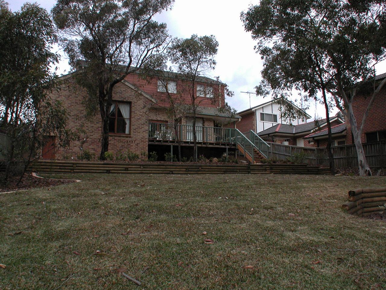 Two storey house located behind a couple of trees and large lawn